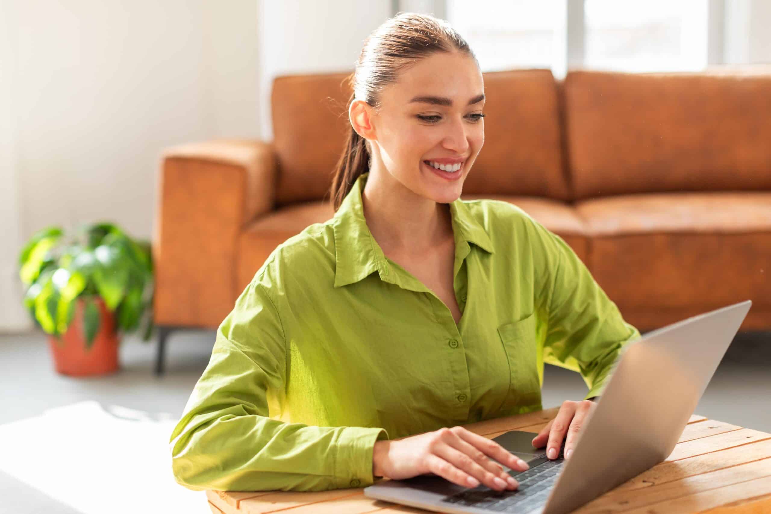 Mujer sentada en una mesa usando un ordenador portátil, representando a una clienta de Lawwwing beneficiándose de las actualizaciones automáticas semanales de la política de cookies y el cumplimiento del RGPD a través del servicio de suscripción de Lawwwing.