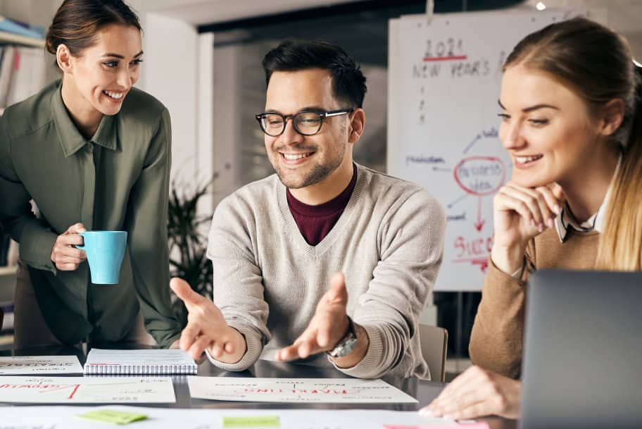 Equipo de marketing colaborando en una sesión de planificación en la oficina, con documentos, una laptop y una pizarra de ideas en el fondo.