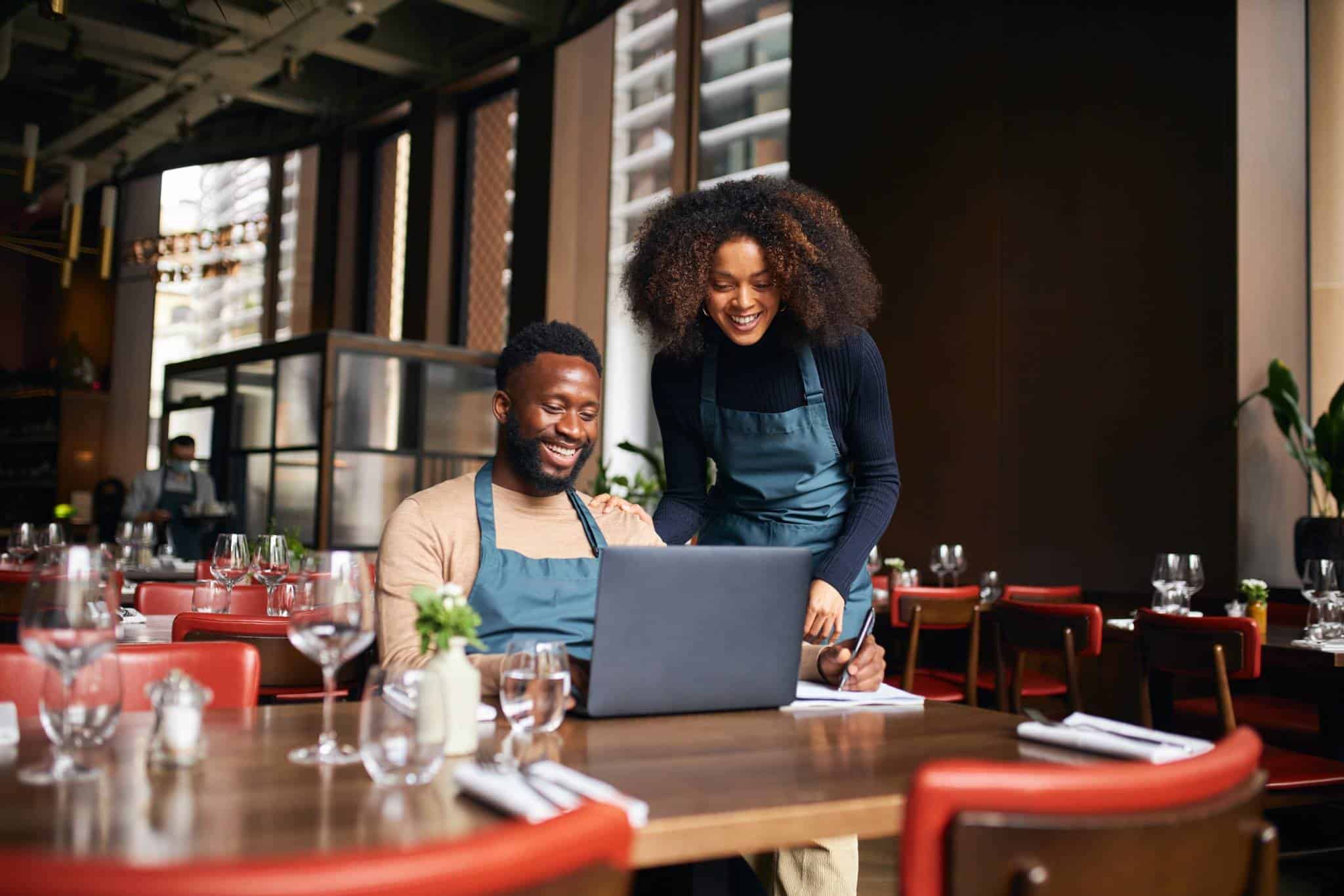 erentes de restaurante trabajando en la gestión digital con un portátil en un ambiente acogedor.