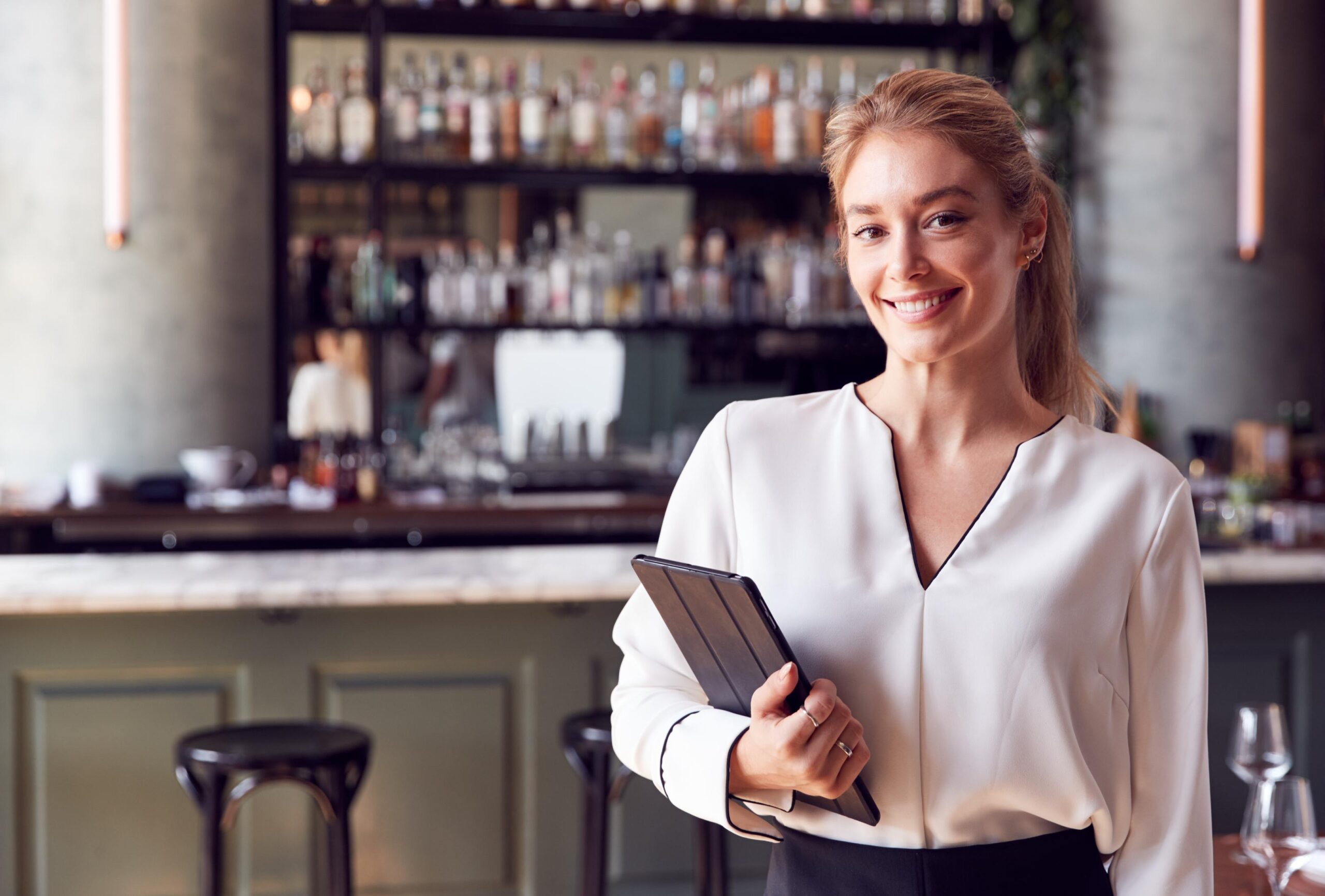 Propietaria de un restaurante sonriendo mientras gestiona su negocio con una tablet